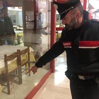 Un carabiniere indica le macchie di sangue sulle vetrate della Galleria Scalo