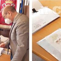 Il sindaco Diego Ferrara legge i fogli contenuti nella busta e il pezzo di carta insanguinato
